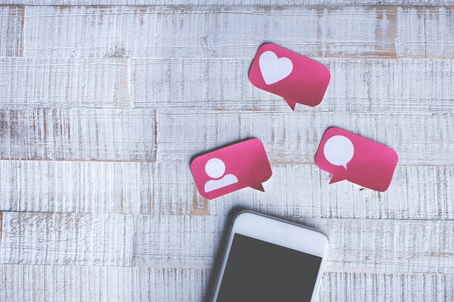 Handy mit aus pPapier ausgeschnittenen Social Media Icons in rosa